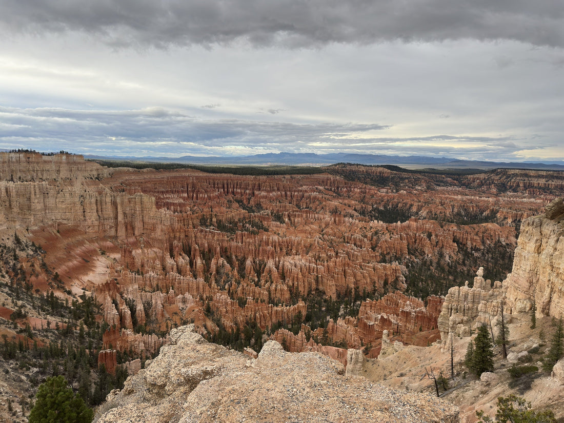 Layered orange and pale rock formations at Bryce Canyon beneath a gray, cloud-filled sky.