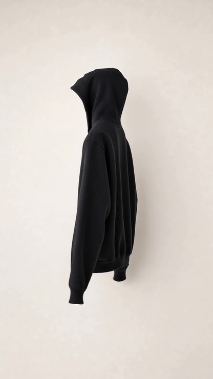 Left-side profile of the SNDGRS STILL. Volume 001 black heavyweight pullover on an off-white background.