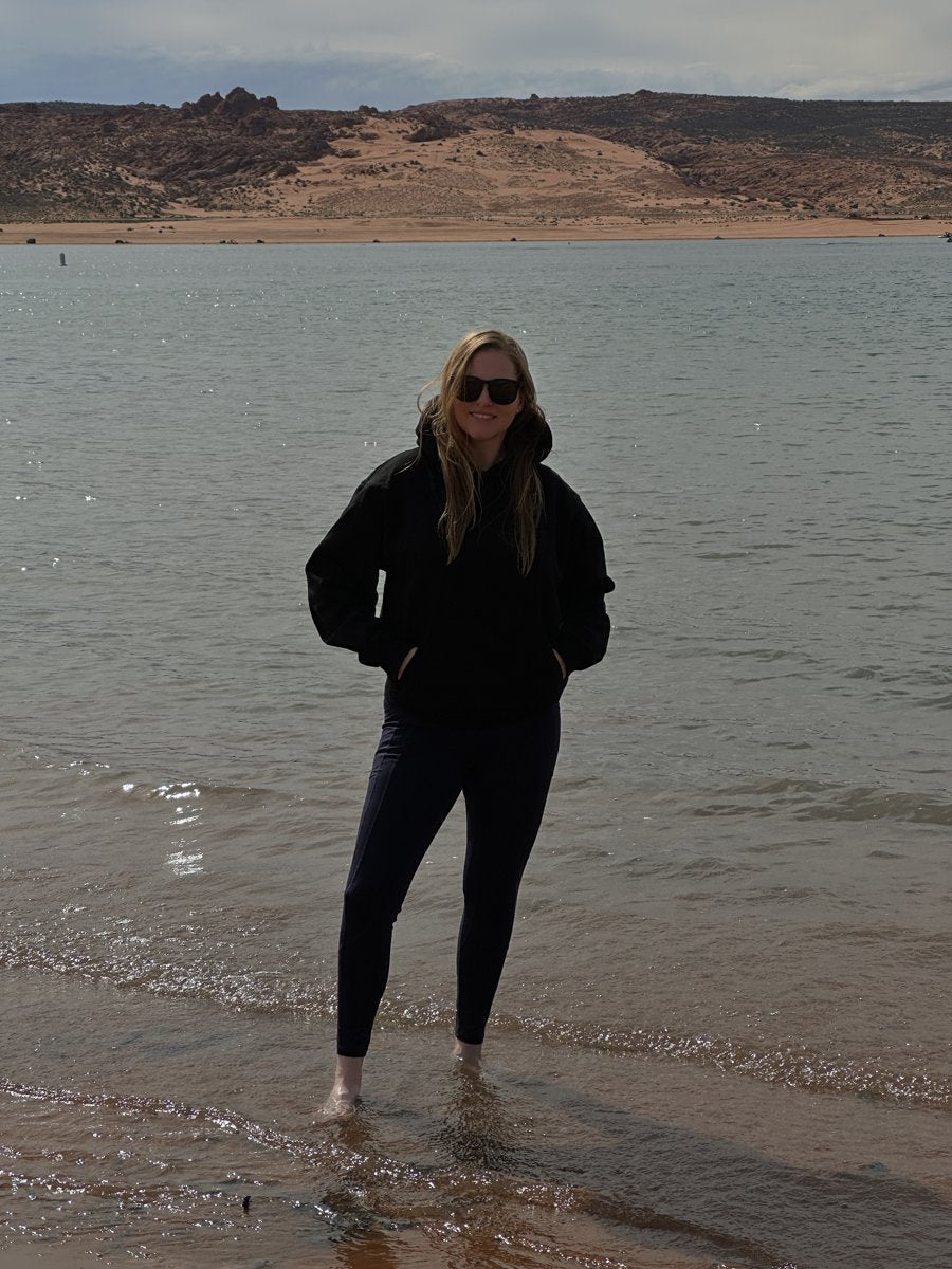 A wearer in a black SNDGRS hoodie beside Sand Hollow Reservoir.